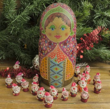 Boyanmış ahşap matrioshka bebek ve balçıktan Noel Baba. Materoska bebeğinin etrafında Noel Baba 'lar var.