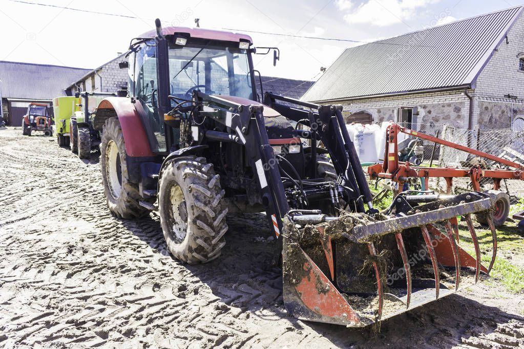 Agricultural machinery and equipment . Tractor with front loader for manure. The yard of a dairy farm. Podlaskie, Poland.