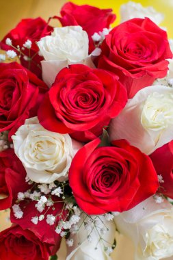 Beyaz ve kırmızı güllerden bir buket gelin ve damadın alyansları