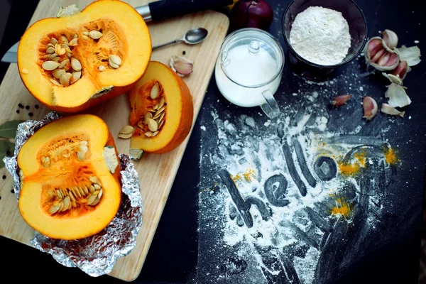 Fresh pumpkin slice on a black wooden table with flour texture. Autumn cooking background. Healthy eating. Top view.