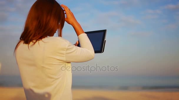 Young female straightens her hair and stares at the plate against the sea — Stock Video