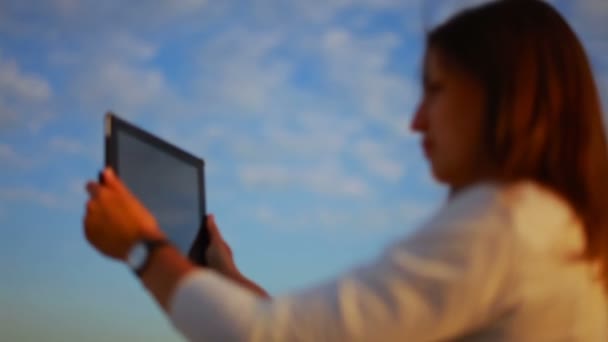 Senhora faz um panorama no tablet contra o pano de fundo do céu azul — Vídeo de Stock