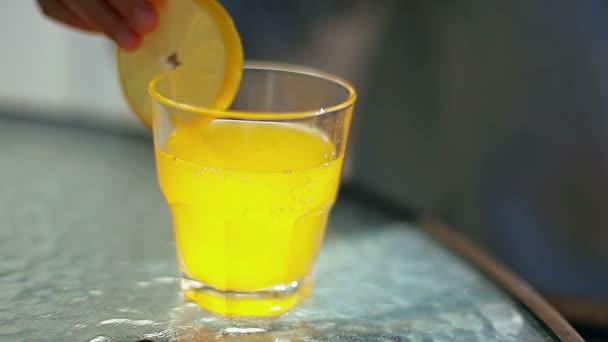 Mains féminines ajoutant du citron et une paille dans un verre avec un cocktail jaune — Video