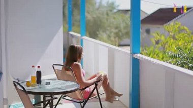 kız pembe bir mayo ona içki sonlandırır ve balkondan dışarı gidiyor