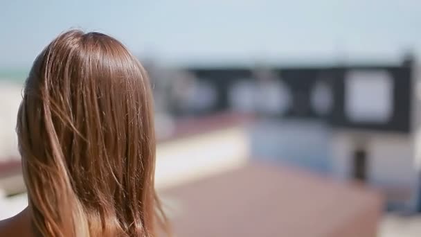 Καστανά μαλλιά που κυματίζουν στον αέρα με φόντο παραλία σπίτια — Αρχείο Βίντεο