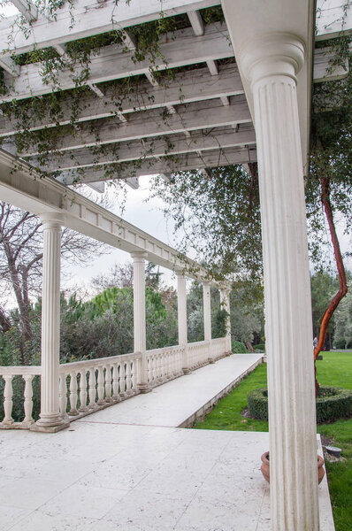 Античная беседка в парке, окруженном южными растениями
