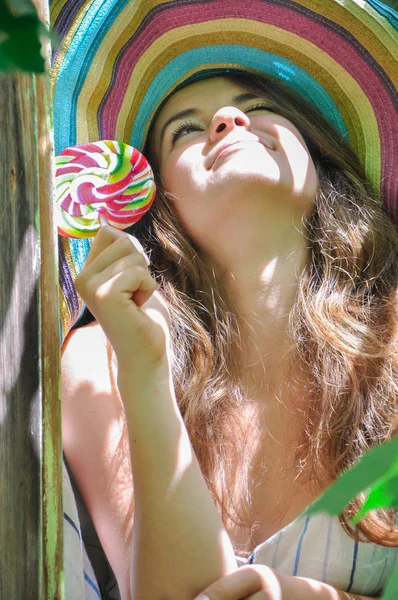 Fille drôle portant un chapeau coloré avec sucette dans la fenêtre avec des feuilles de raisin — Photo