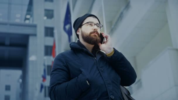 Hombre de teléfono inteligente hablando por teléfono en frente del centro de negocios — Vídeos de Stock