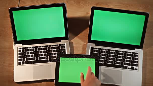 Mann scrollt und zoomt Bilder auf digitalem Tablet auf zwei Laptops liegend — Stockvideo