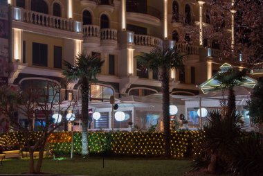 restoranın arka planında palmiye ağaçları ve ışıklar ile dekore edilmiş otel