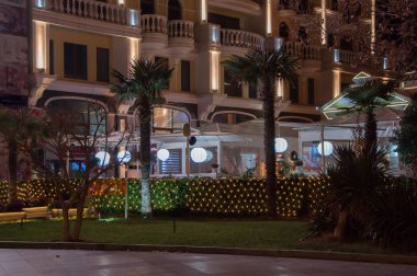 restoranın arka planında palmiye ağaçları ve ışıklar ile dekore edilmiş otel