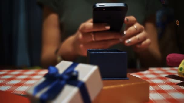 Крупним планом жінка робить фотографію на смартфоні маленької синьої секретної подарункової коробки — стокове відео