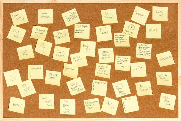 Un montón de pegatinas para notas con texto en un tablero de corcho —  Fotos de Stock