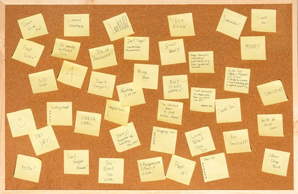 Un montón de pegatinas para notas con texto en un tablero de corcho —  Fotos de Stock