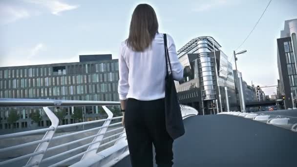 Hermosa chica caminando en un puente en un centro de la ciudad ocupado — Vídeo de stock