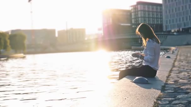 Schönes Mädchen, das ein Foto auf dem Smartphone macht, sitzt in der Nähe des Flusses — Stockvideo