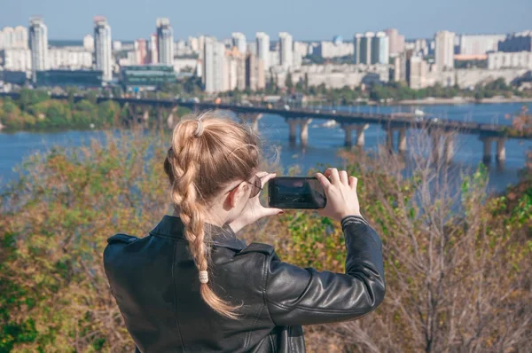 Hermosa chica rubia haciendo fotos de la ciudad en un teléfono inteligente — Foto de Stock