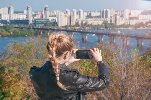 Hermosa chica rubia haciendo fotos de la ciudad en un teléfono inteligente — Foto de Stock