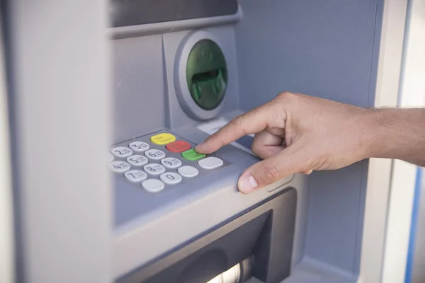 Hand entering personal identification number on ATM dial panel