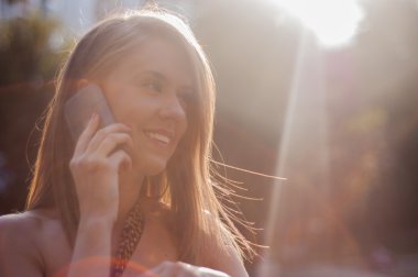 Genç bir kadın cep telefonuyla konuşuyor.