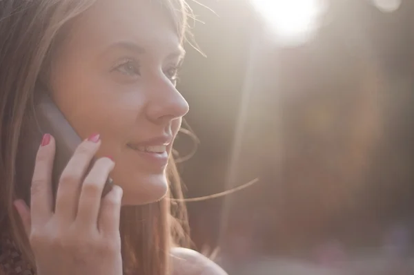 Hermosa joven mujer sonriendo y hablando en el teléfono celular en soleado — Foto de Stock
