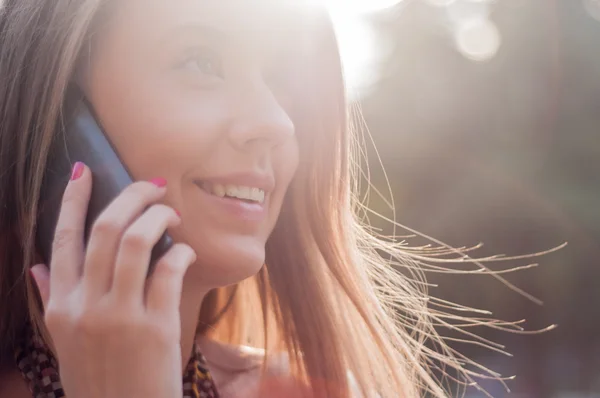Hermosa joven mujer sonriendo y hablando en el teléfono celular en soleado — Foto de Stock