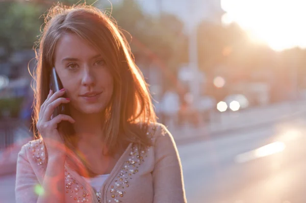 Mujer joven hablando por teléfono celular sobre el fondo de la ciudad . — Foto de Stock