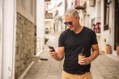 Bir akıllı telefon ve kahve, açık tutan güzel yakışıklı adam