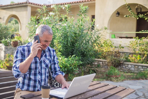 Bedrijf, internet, media, mensen en technologie concept - close up van zakenman op laptopcomputer met nieuws web-pagina op het scherm buiten op het zomerterras en drinken koffie — Stockfoto