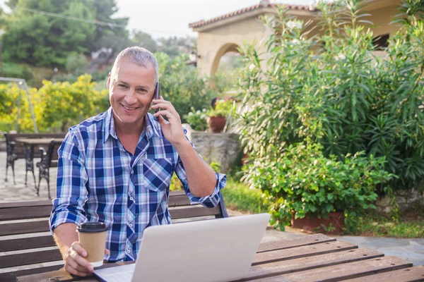 Man met laptop en koffie in zomer park op heldere dag — Stockfoto