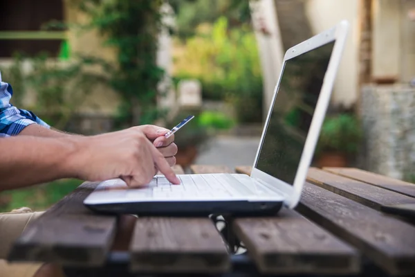 Close-up iemands handen houden van een credit card en toetsenbord van de computer te gebruiken voor online winkelen, buiten — Stockfoto