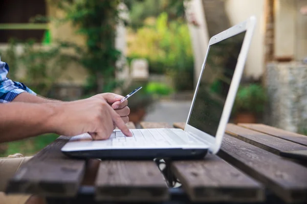 Geld en technologie. Jonge man houden creditcard en het gebruik van laptopcomputer. — Stockfoto