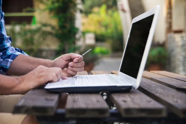 Knappe man ontspannen in zijn tuin met behulp van laptop om te winkelen op een zonnige dag — Stockfoto