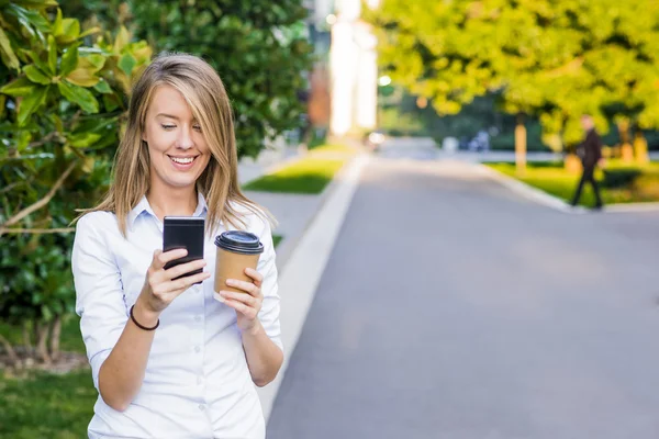 Onun smartphone kullanarak ve güneşli mavi gökyüzü karşı ayakta çalışma klasörleri taşıyan neşeli bir işkadını portresi yukarıya kapatmak. — Stok fotoğraf