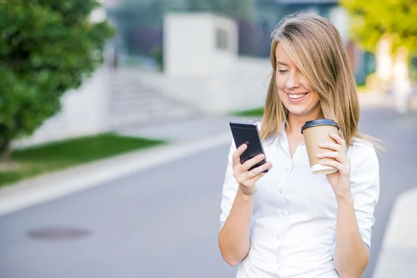 Jeune femme intelligente professionnelle lisant en utilisant le téléphone. Femme d'affaires lisant des nouvelles ou textos sms sur smartphone tout en buvant du café pendant la pause du travail. — Photo