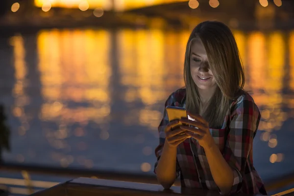 Smartphone şehirde geceleri kullanan kadın. Kadın telefonda kısa mesaj gönderme — Stok fotoğraf