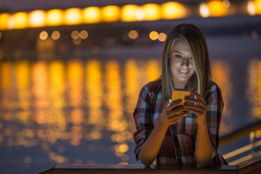 Akıllı telefon mobil şehirde geceleri kullanan genç ve güzel kız