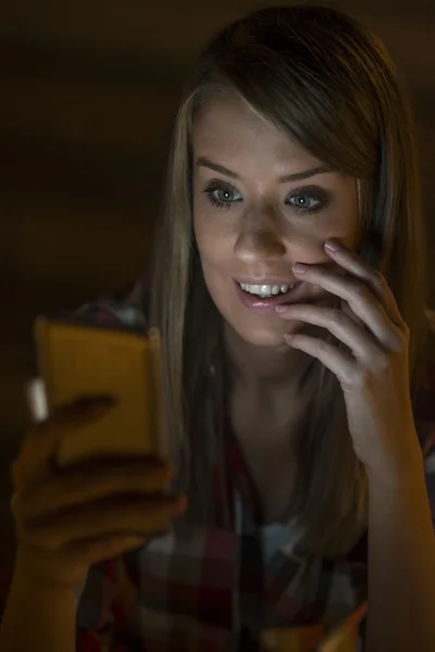 Splendida giovane donna in piedi con il telefono cellulare all'aperto di notte, studentessa caucasica che legge messaggi di testo sul suo telefono cellulare con riflesso sulla sua luce dello schermo facciale, telefono schermo vuoto — Foto Stock