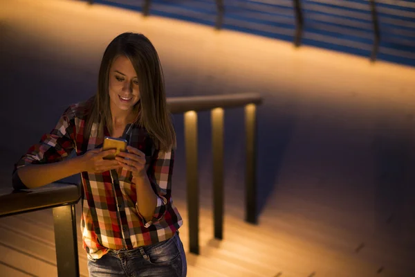 Feminino estudante caucasiano ler mensagens de texto no telefone celular com refletido em sua luz de tela de rosto, telefone de tela em branco — Fotografia de Stock