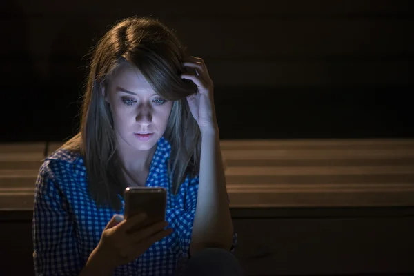 Sad news. Upset young woman with mobile phone reads the message. Night portrait in the Park