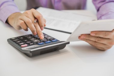Bir hesap makinesi kullanma ve evde çalışırken onun not defterinde yazma yakışıklı ihtiyar görüntü kırpılmış