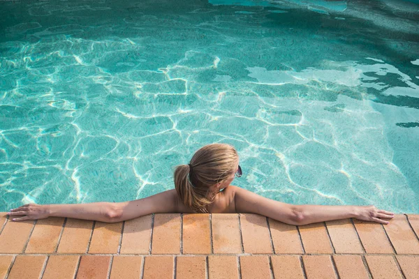 Una joven hermosa mujer se relaja en la piscina. Concepto de bienestar. Spa y relax, felicidad de la mujer . — Foto de Stock