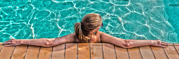 A young beautiful woman relaxes at the swimming pool. Wellness concept. Spa and relax, woman happiness.