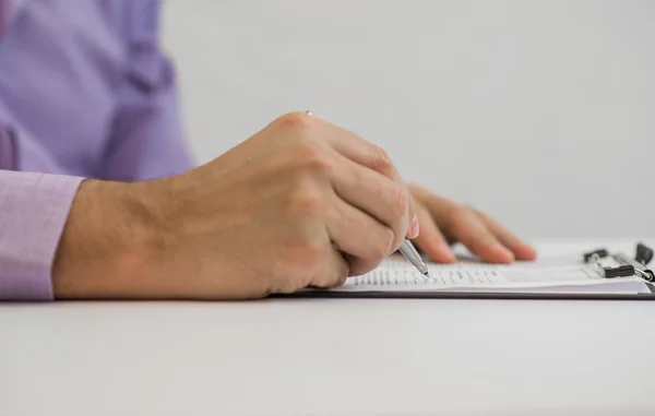 Empresário escreve em um caderno enquanto está sentado em uma mesa — Fotografia de Stock