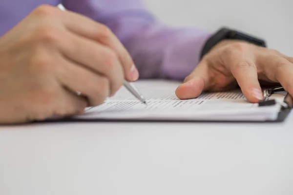 Az üzletember jegyzetfüzetbe ír, miközben egy asztalnál ül. — Stock Fotó