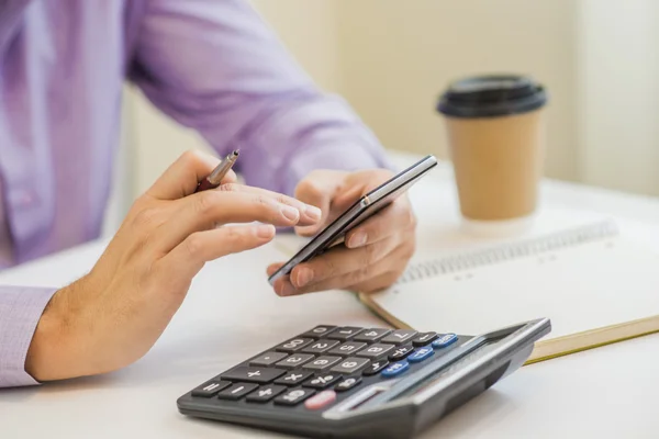 Homem maduro com calculadora, fiscal livreto de renda e xícara de café na mesa — Fotografia de Stock