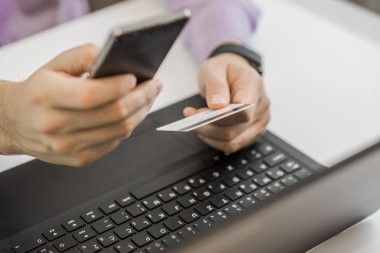 Elleri plastik kredi kartı tutuyor ve dizüstü bilgisayar kullanıyor. Çevrimiçi alışveriş kavramı.