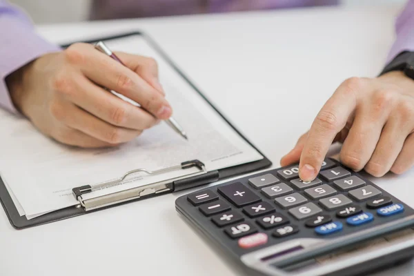 Close-up de empresário calculando faturas usando calculadora — Fotografia de Stock