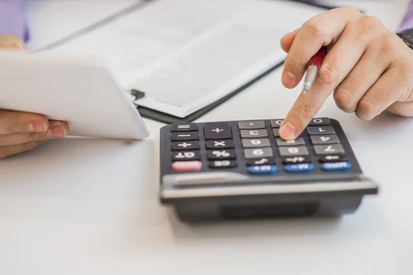Close up, homem de negócios ou advogado contador trabalhando em contas usando uma calculadora e escrevendo em documentos — Fotografia de Stock