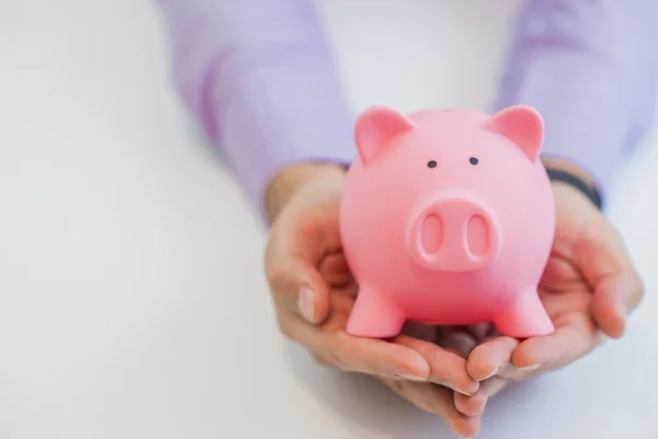 Empresário segurando um banco porquinho em suas mãos símbolo de poupança e bons investimentos — Fotografia de Stock